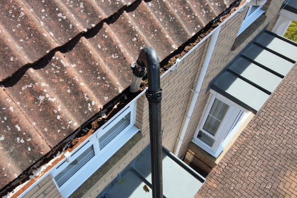 Gutter clearing service removing compacted leaves and debris from a residential gutter in East Kilbride
